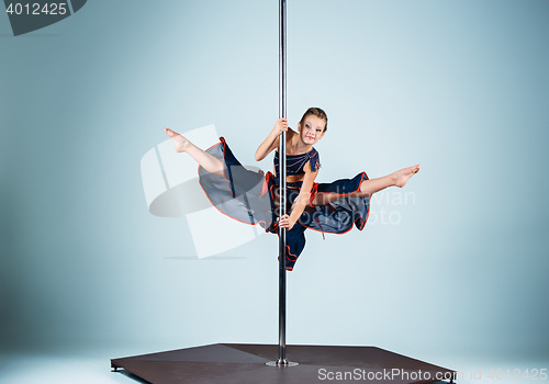 Image of The strong and graceful young girl performing acrobatic exercises on pylon