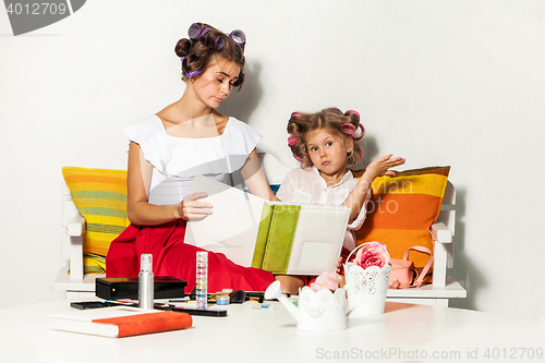 Image of Little girl sitting with her mother and looking at a photo album