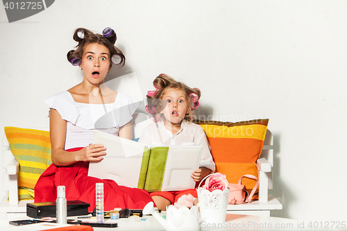 Image of Little girl sitting with her mother and looking at a photo album