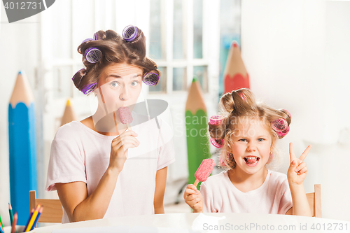 Image of Little girl sitting with her mother and eating ice cream
