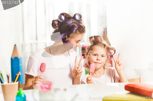 Image of Little girl sitting with her mother and eating ice cream