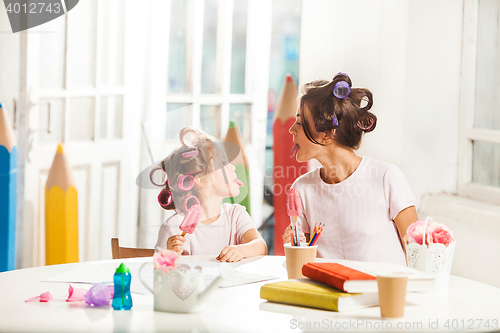 Image of Little girl sitting with her mother and eating ice cream