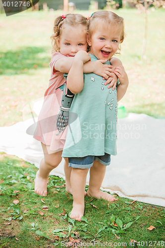 Image of The two little baby girls playing against green grass