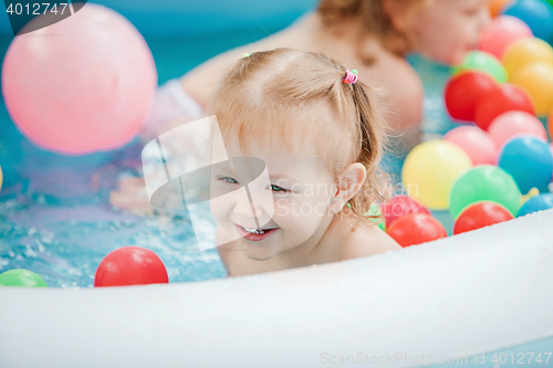 Image of The little baby girl playing with toys in inflatable pool in the summer sunny day