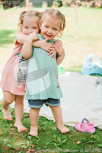 Image of The two little baby girls playing against green grass