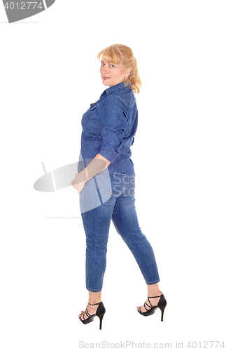 Image of Woman in jeans clothing standing.