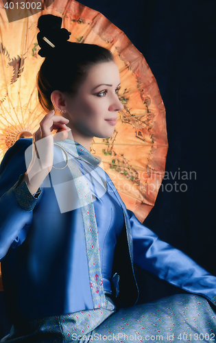 Image of Young Woman Sitting With a Chinese Umbrella