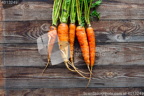 Image of Raw carrot with green leaves on wooden background