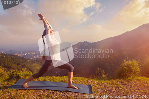 Image of Woman doing yoga asana Virabhadrasana 1 - Warrior pose outdoors