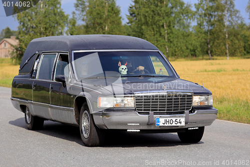 Image of Cadillac Fleetwood Funeral Vehicle Driving Along Rural Road