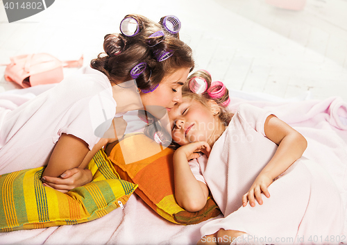 Image of Little girl with her mother slipping in bed