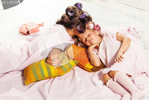 Image of Little girl with her mother slipping in bed