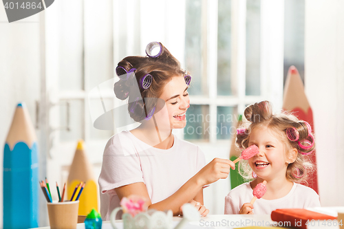 Image of Little girl sitting with her mother and eating ice cream