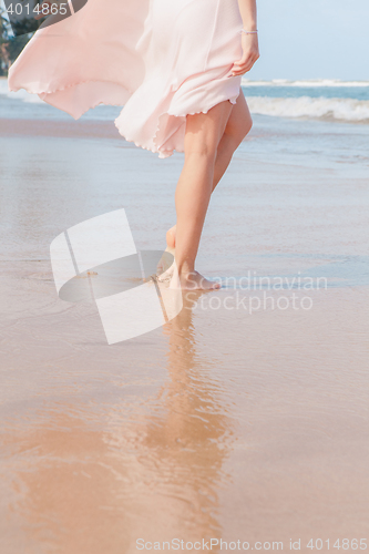 Image of Woman legs walking on the beach sand