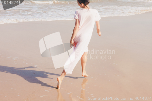 Image of Woman legs walking on the beach sand