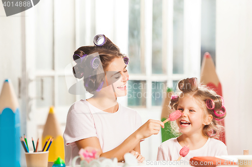 Image of Little girl sitting with her mother and eating ice cream
