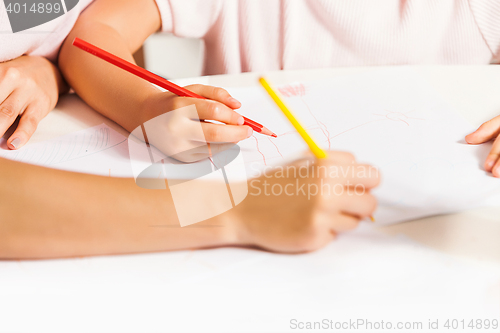 Image of The young mother and her little daughter drawing with pencils at home