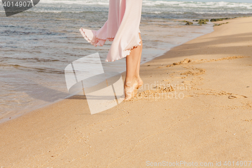 Image of Woman legs walking on the beach sand