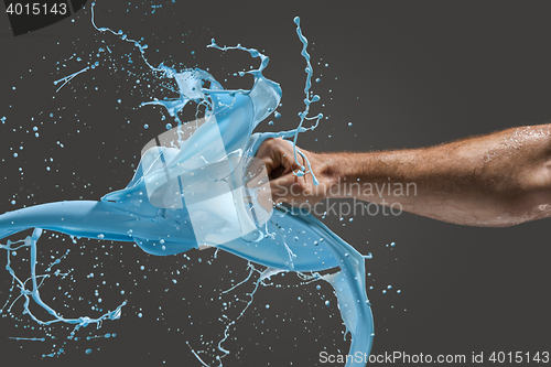 Image of Close-up of a man\'s fist punching through liquid