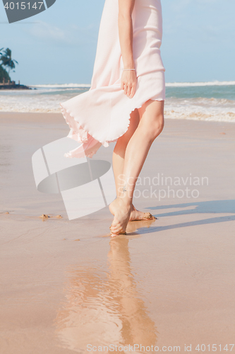 Image of Woman legs walking on the beach sand