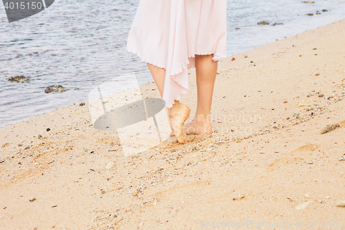 Image of Woman legs walking on the beach sand