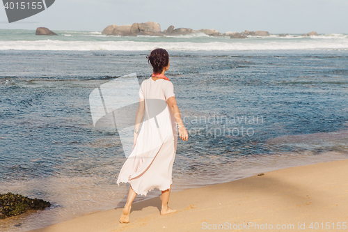 Image of Woman walking on the beach sand