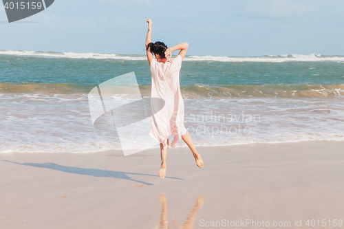 Image of Woman walking on the beach sand