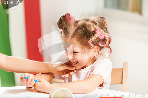 Image of The young mother and her little daughter drawing with pencils at home