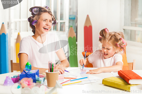 Image of The young mother and her little daughter drawing with pencils at home