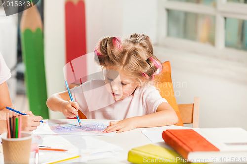 Image of The young mother and her little daughter drawing with pencils at home