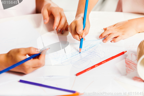 Image of The young mother and her little daughter drawing with pencils at home