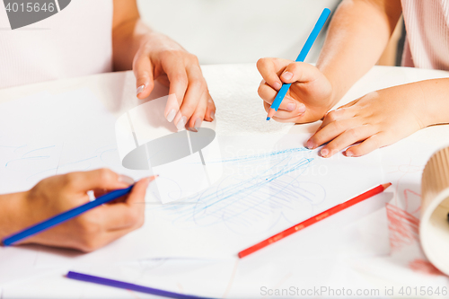 Image of The young mother and her little daughter drawing with pencils at home