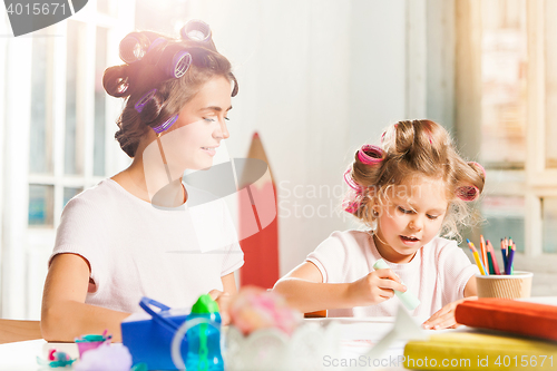 Image of The young mother and her little daughter drawing with pencils at home