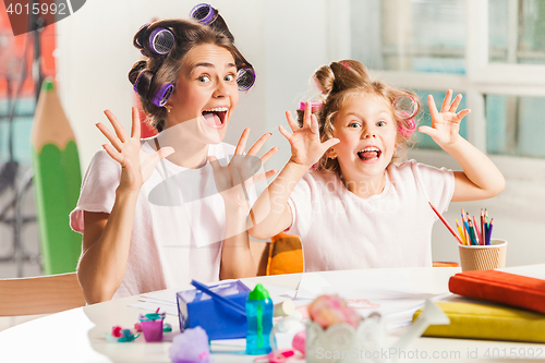 Image of The young mother and her little daughter drawing with pencils at home
