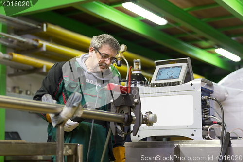 Image of Industrial worker setting orbital welding machine.