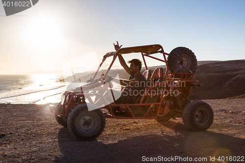 Image of Man driving quadbike in sunset.