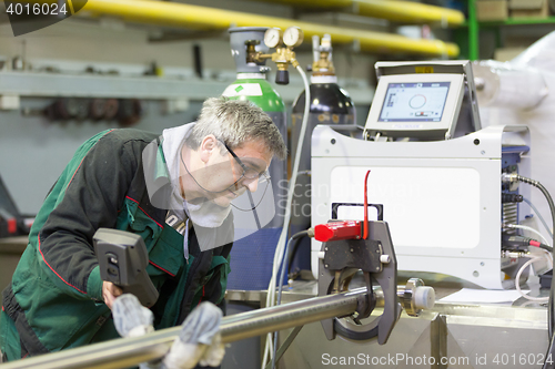 Image of Industrial worker setting orbital welding machine.