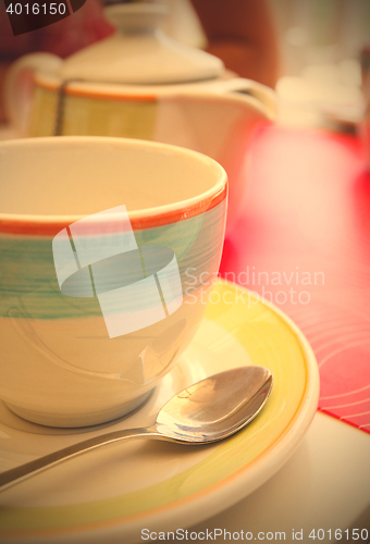 Image of tea cup with a spoon of sugar on table