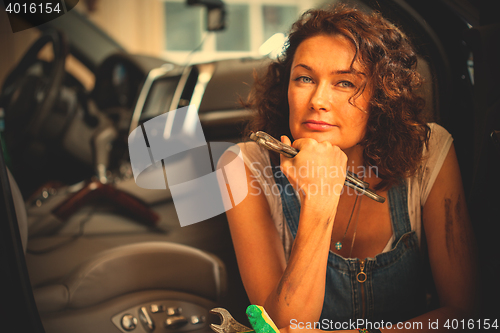 Image of Portrait of a handsome mechanic in blue overalls with a wrench