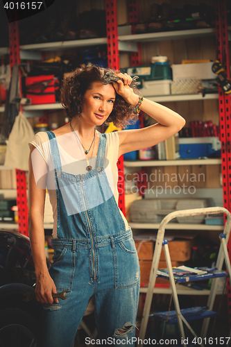 Image of beautiful woman in blue overalls in the interior of the garage