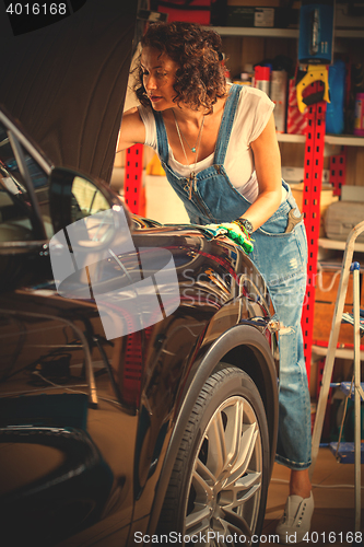 Image of Mechanic woman opened the hood of the car