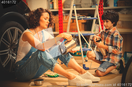 Image of Mechanic woman pours tea from a thermos into a cup for the child