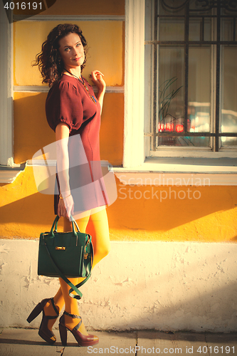 Image of smiling middle-aged woman in a burgundy dress and handbag