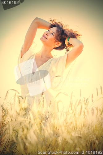 Image of pretty happy woman in bright clothing among spikes in field