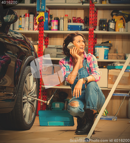 Image of pretty woman mechanic talking on mobile with client