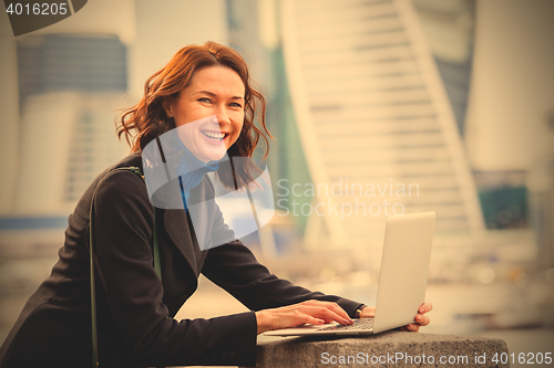 Image of portrait of a beautiful laughing woman with a laptop