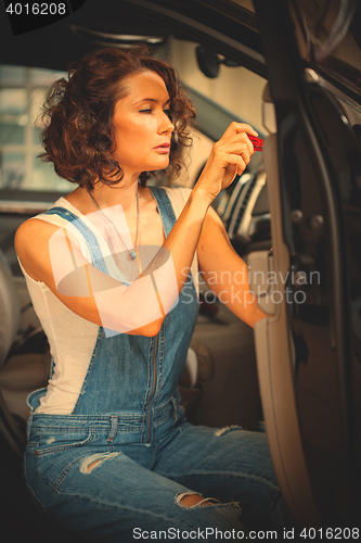 Image of mechanic woman in a blue overalls repair with a screwdriver the 