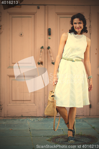 Image of smiling dark-haired middle-aged woman dressed in a light summer 