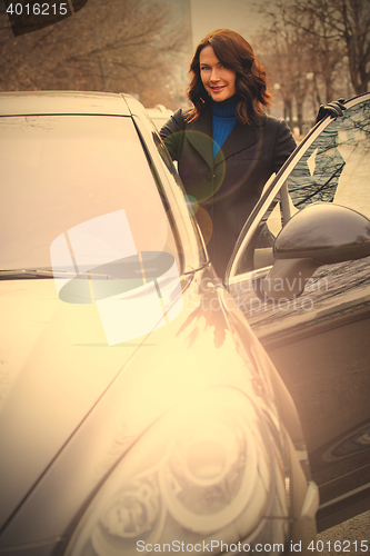 Image of smiling woman in a dark coat opened the car door