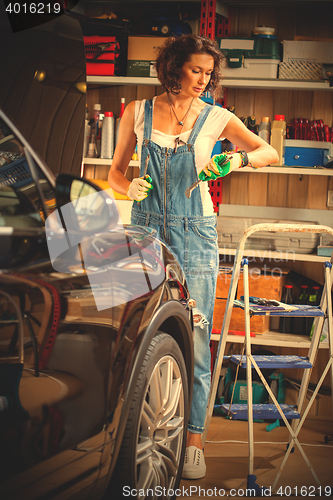 Image of mechanic woman working on a car in an auto repair shop